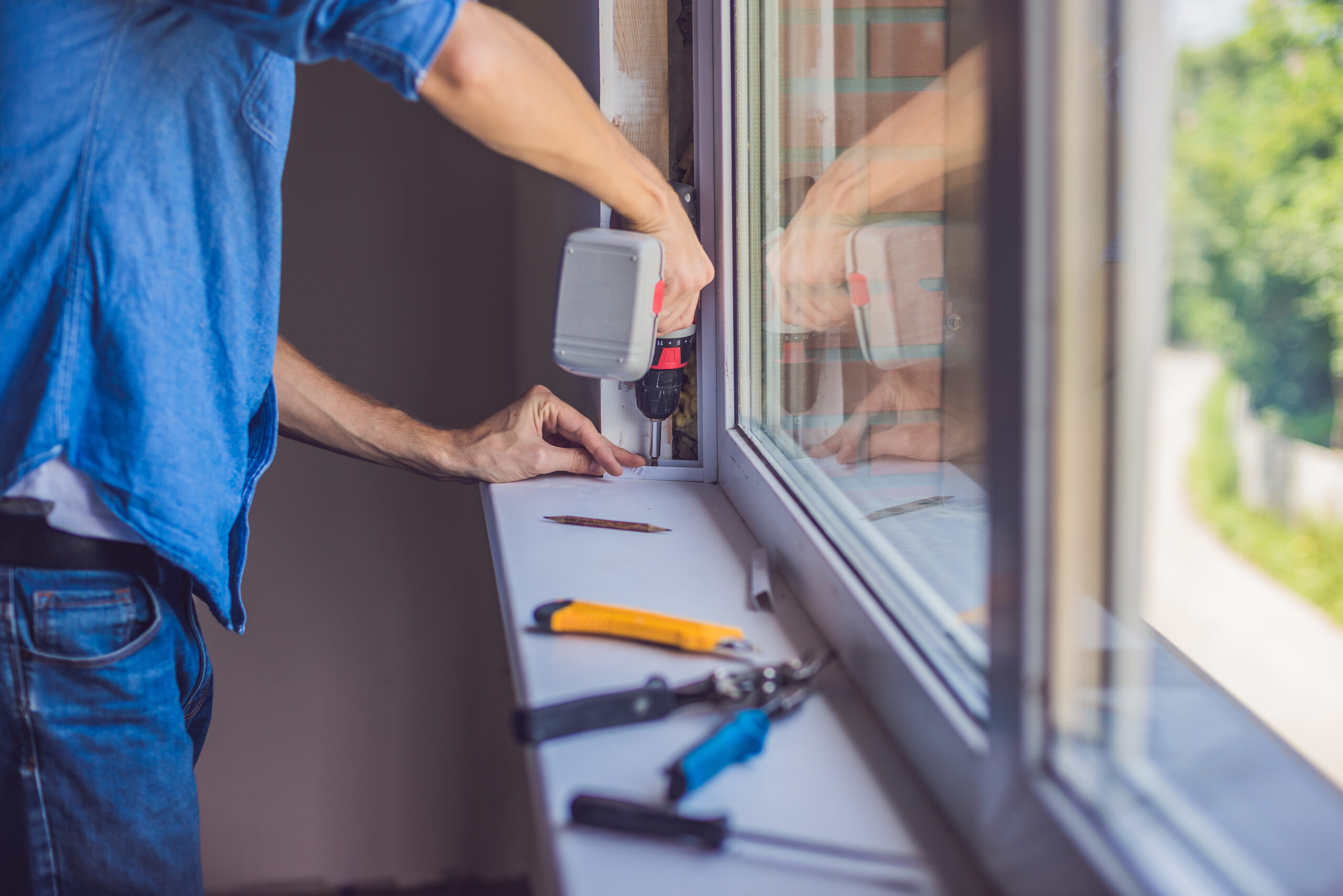 Man in a blue shirt does window installation.